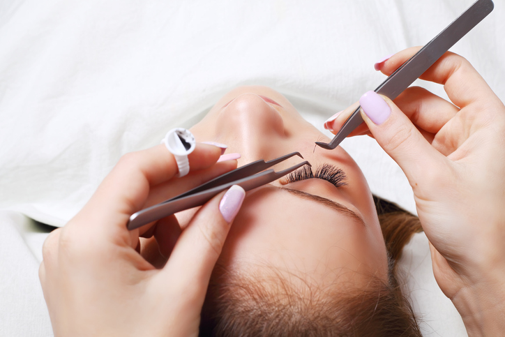 an aesthetician doing eyelash extensions for a customer